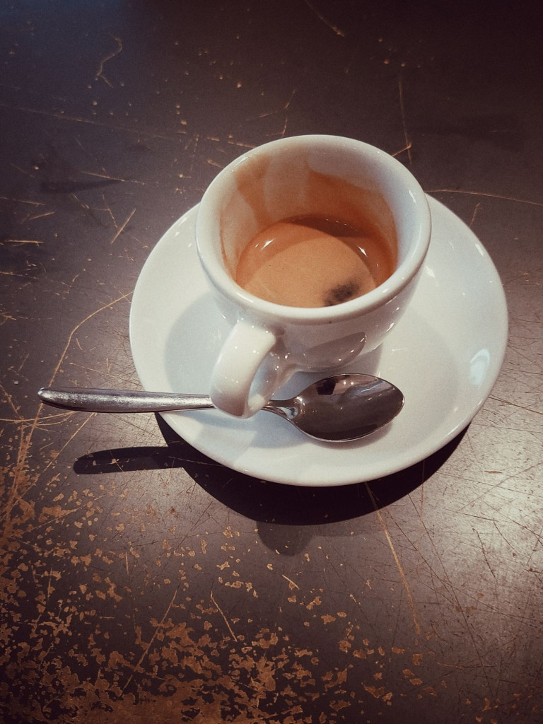 An espresso cup on a worn-down table.