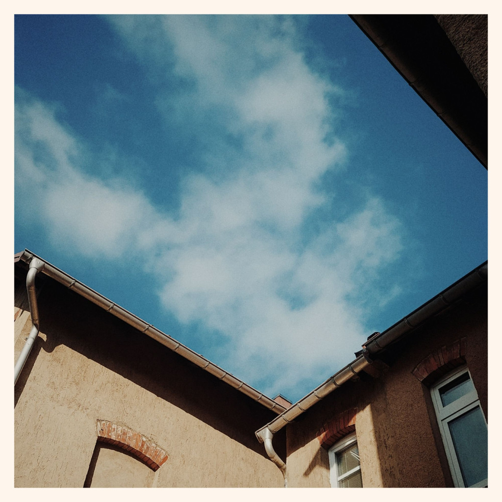 Blue sky and white clouds in between old roofs.