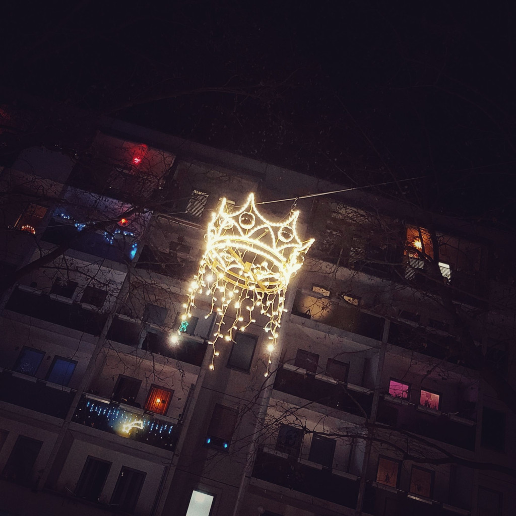 A crown of lights in front of the facade of an East Modernist appartement house.