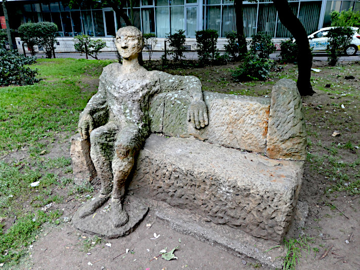 Foto van beeld van bank met zittende figuur met arm nonchalant over de rugleuning