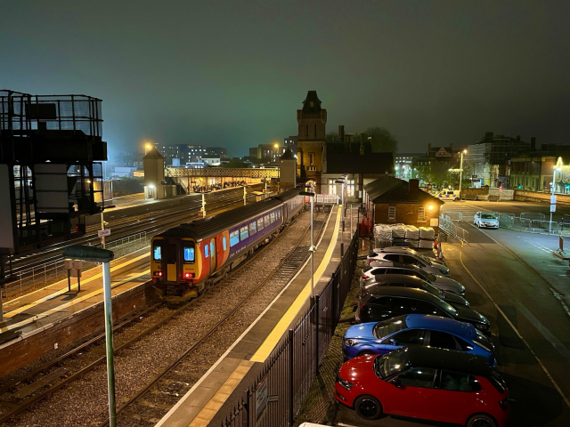 Lincoln train station. Night shot, a train is ready to leave. Green light in the sky frame an overall orange nuance created by the artificial station illumination
