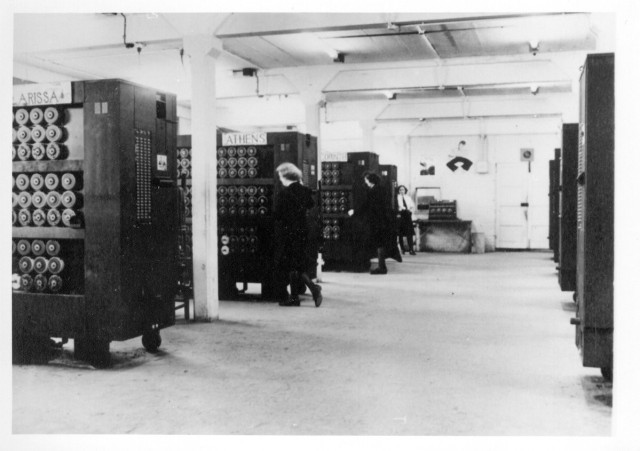 Photo of racks of bombes (early computers) with WRNS standing at the end of some of them.