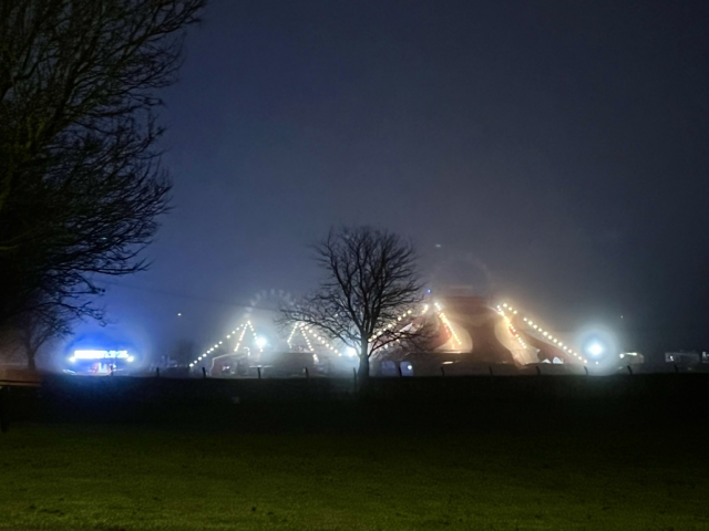 A circus tend, in a park, shrouded in the mist. A surreal experience at night.