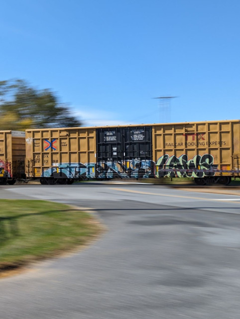 A train with graffiti speeding by across the road