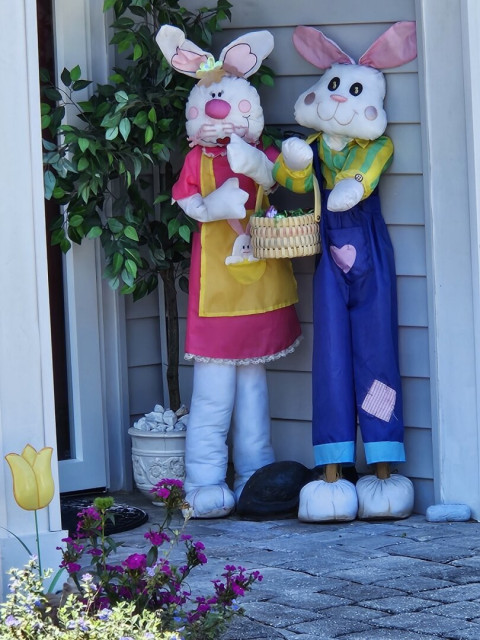 The porch and home's entryway decorated for Easter with potted flowers and tulip decorations, with visitors greeted by two large bunnies dressed as Mrs. and Mr. Easter Bunny.