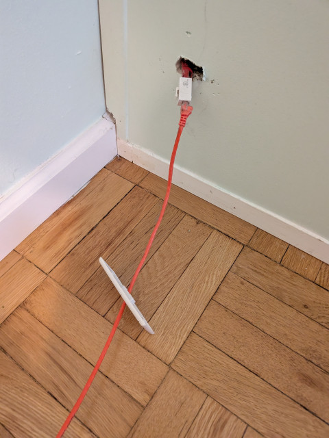 A very unprofessionally installed cat6 cable going through a fake wall