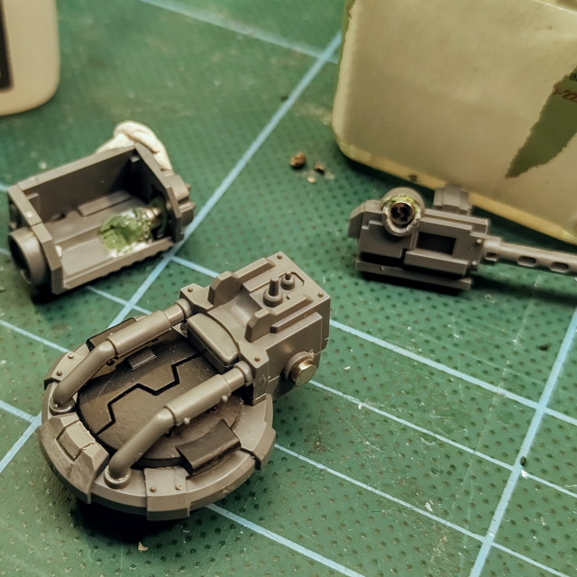 A close-up photo of three plastic parts for a gun turret. There are magnets glued in place for easy swapping between weapon loadouts.