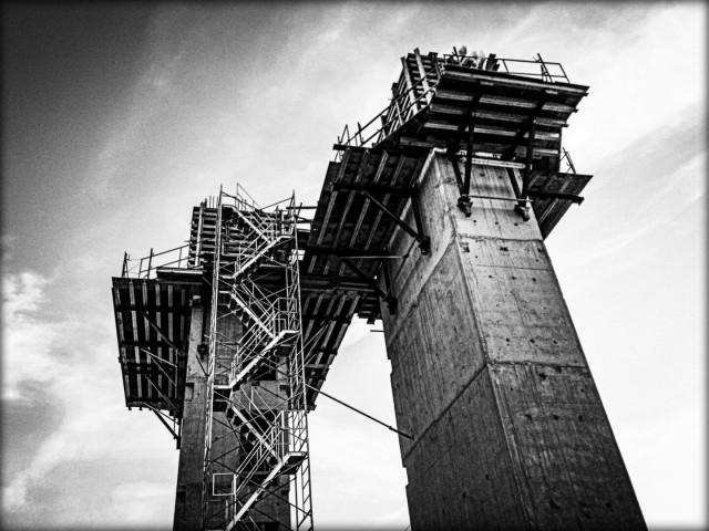 Looking up at two large elevator shafts in an apartment building being constructed in this black and white photo.