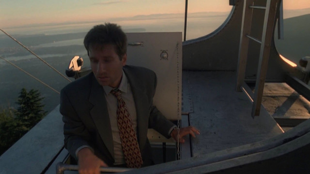 X-Files' Mulder in a cable car on Grouse Mountain outside Vancouver, with an inland sea in the background.