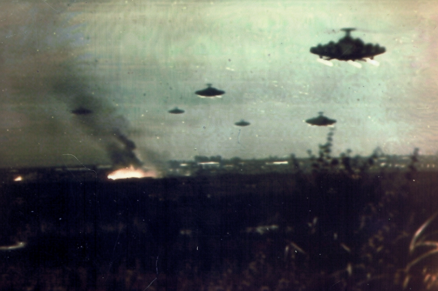 Flying saucers on the outskirts of a large town, over burning fields