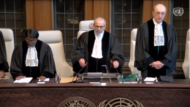 Three members of the International Court of Justice in formal dress stand ready for the proceedings to start