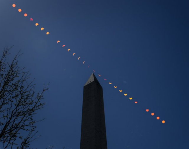 Timelapse photo of sun moving across the sky over the Washington Monument. Each disc has a little bite taken out of it until it reaches the top of the monument then each disc gets fuller. There are about 8 discs on each side all lined up in a straight line across the sky 