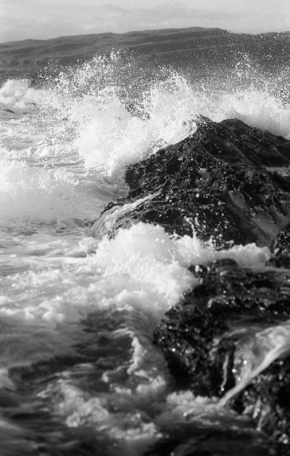 Ocean waves crashing onto a rocky shoreline in black and white. Ilford FP4 shot with a Minolta X700 and developed in Ilford DDX.