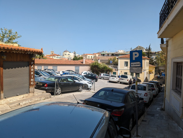 Photo of Τριποδοn street in Athens with lots of parked cars, a surface parking lot, and two parking signs. 