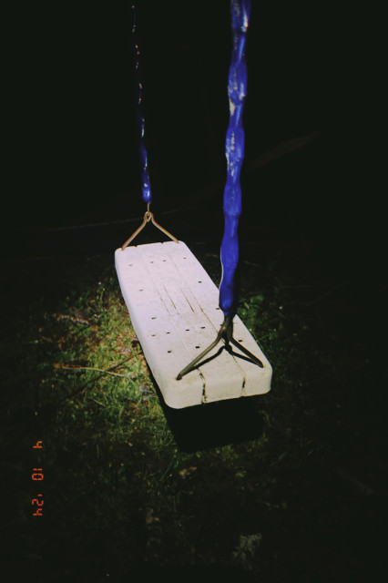 A white straight swing with blue covered chains sits similarly