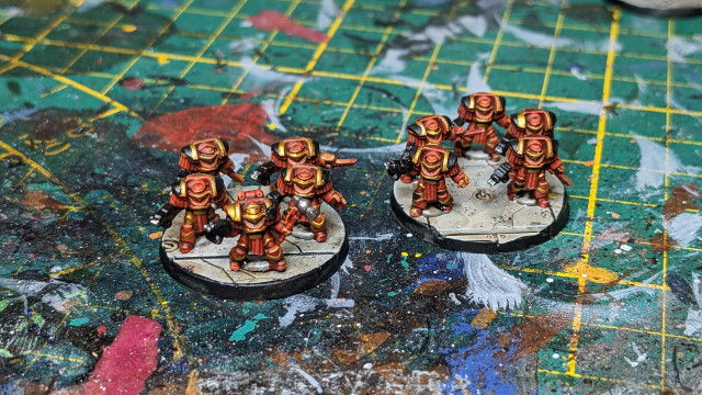 Two grey bases of Blood Angels Terminators painted in red with black and gold details.