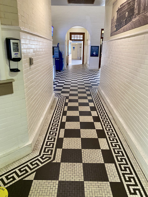 Intricate black and white tile patterns on the floor and walls in a hallway leading between lobby and waiting room.