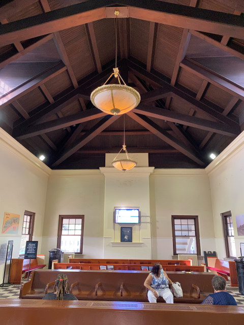 Lofted ceiling with wooden rafters and chandeliers in the waiting room.
