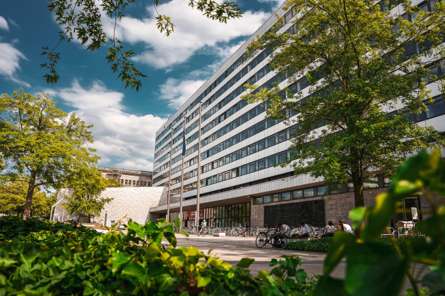 Seitliche Ansicht des Hauptgebäudes der Technischen Universität, umgeben von Bäumen.