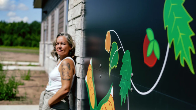 Artist Sarah Agaton Howes, whose well-known Ojibwe lifestyle brand, “Heart Berry,” works in partnership with Eighth Generation, stands by a mural she painted on the front of Anishinaabetwaakamig, the Language and Cultural Center for the Fond du Lac Band of Lake Superior Chippewa in Minnesota. (Photo by Nedahness Greene, courtesy of Sarah Agaton Howes)