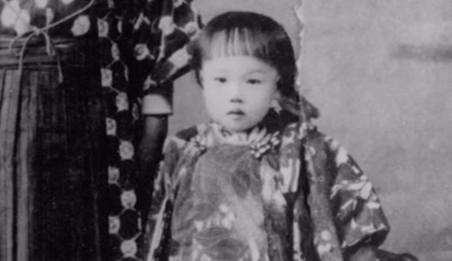 Photo of Saruhashi when she was a little girl. It's a close-up of her in a family photo, and she is standing next to an adult. Both are wearing traditional clothes.
