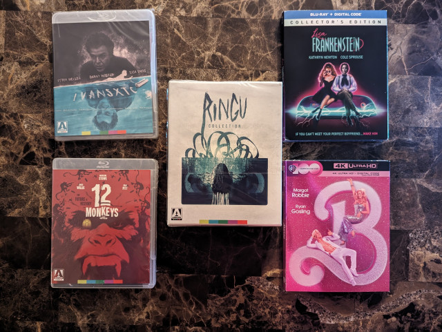 Five movie blu-ray cases. From left to right, they are: ivans xtc.; 12 Monkeys; The Ringu Collection; Lisa Frankenstein; Barbie.