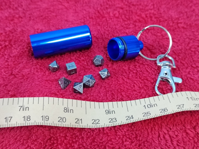 Oh.  That's its use.  It contains a full set of gunmetal RPG dice: d4, d6, d8, d10s (one 00-99, the other 0-9), d12, and d20.  These are minuscule, as the tape measure in the photo shows, with average spans of 7-8mm.