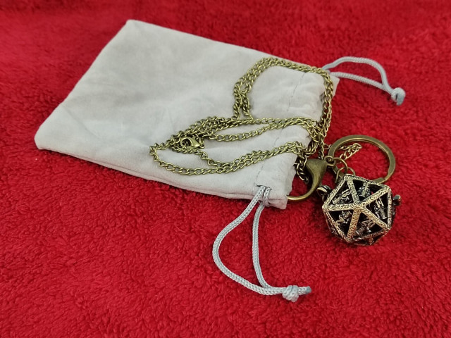 A faux-bronze fancy sculpted d20-shaped pendant on a long brass chain.

What use is this?