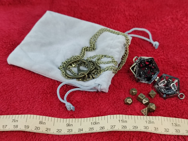 Oh.  That's its use.  It contains a full set of faux-bronze RPG dice: d4, d6, d8, d10s (one 00-99, the other 0-9), d12, and d20.  These are minuscule, as the tape measure in the photo shows, with average spans of 7-8mm.