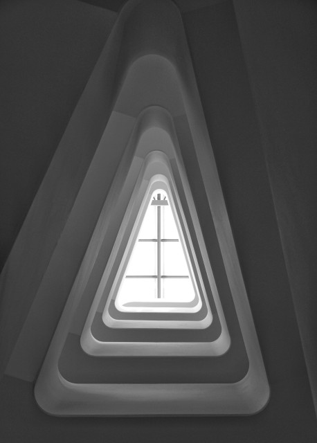 Schwarz-Weiß-Foto. Blick auf ein dreieckiges Fenster mit abgerundeten Ecken. 