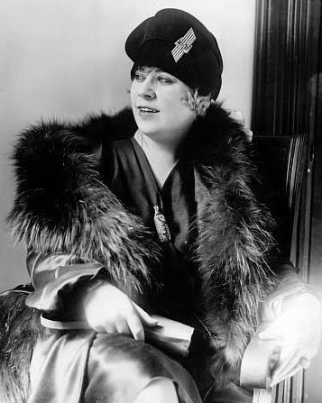 Mae West around the time of her trial. She is a white woman with blonde hair tucked under a dark hat. 