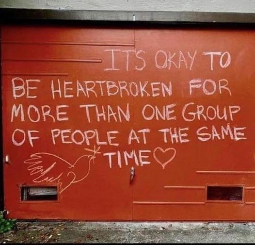 grafiti on a wall that says "It's okay to be heartbroken for more than one group of people at the same time" with a heart and a peace dove