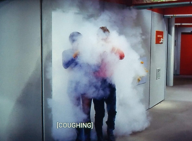 The Original Series corridor is pictured. A room door is open, and spilling out into the hallway are 2 officers in uniform, red and blue uniforms, but otherwise indecipherable because they are entirely enveloped in a big cloud of smoke. It's pouring out all around them and into the hallway area. Heh. Closed caption reads, "[coughing]"