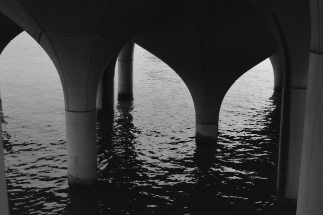 Concrete columns underneath an artificial island, rising out of the water.