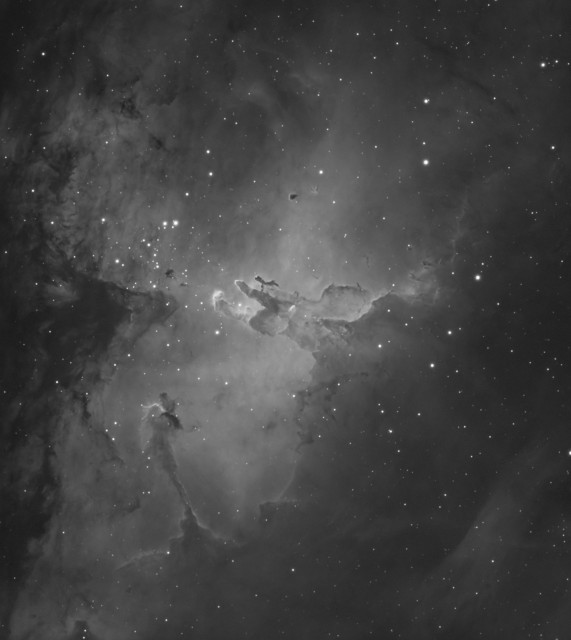 A monochrome image of a part of a space nebula, showing complex clouds structures and roughly hand/finger-shaped gas pillars.