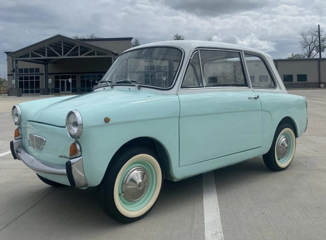 1965 Autobianchi Bianchina Berlina. A tiny little Italian two-door, with cute bug-eye headlights. This one's light blue, with a white roof.
