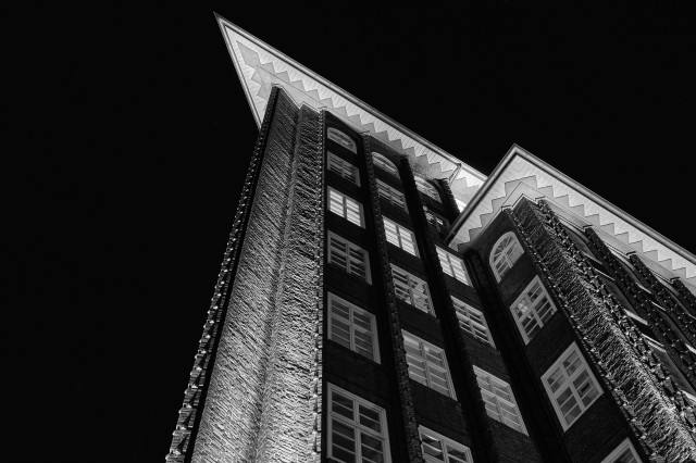 Fassade vom Chilehaus bei Nacht. In einem Stockwerk ist noch Licht.