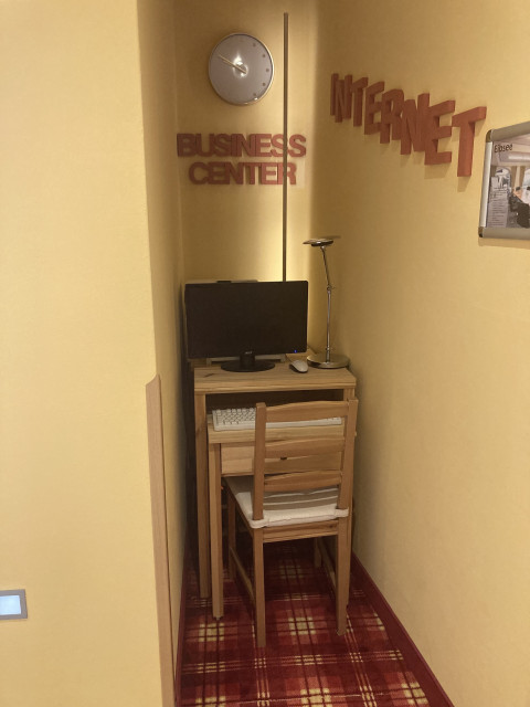 An outdated PC workstation in an extremely narrow niche (maximum width 50 cm) with the words "Business Center" and "Internet" on the walls. 