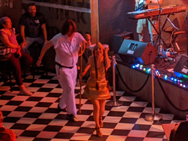 People dressed as The Dude and Maude from The Big Lebowski dancing the dance floor in front of the stage.