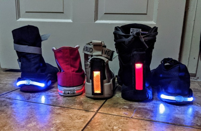 Five different shoes/boots with lights of various colors on the heel of each. Some of the lights are vertical and some horizontal.