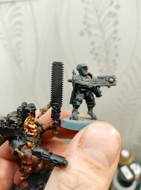 A Tau Fire Warrior next to a Space Marine chainsword. The sword is bigger than the Tau model.