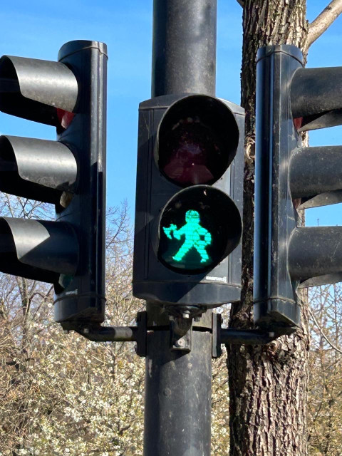 Photo of a traffic light at a pedestrians' crossing in the form of a green Viking with helmet, sword, and shield.