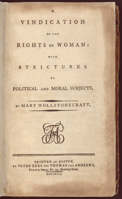 An old, worn book opened to the title page which reads "A VINDICATION OF THE RIGHTS OF WOMAN: WITH STRICTURES ON POLITICAL AND MORAL SUBJECTS. BY MARY WOLLSTONECRAFT. PRINTED AT BOSTON, BY PETER EDES FOR THOMAS AND ANDREWS, FAUST'S STATE, NO. 45, NEWBURY-STREET, MDCCXCIX." The text is in black capital letters centered on the page with a decorative monogram between the author's name and the printer information.