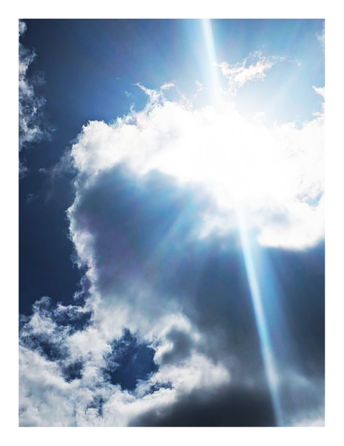 a section of sky at midday. the sun burns and casts rays from behind a white cloud,  
