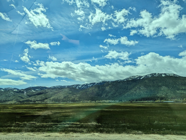 A photo of mountains and a grassy field. There are weird colorations due to the photo being taken from behind a window.