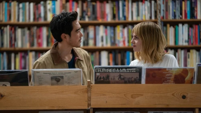 A man and a woman at a record store staring at each other like they want to have a cheeseburger and fries together.
