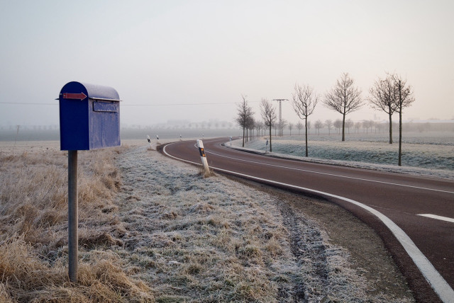 Ein kalter Februartag auf dem flachen Land, Raureif, am Rand einer unbefahrenen Landstraße steht ein Briefkasten.