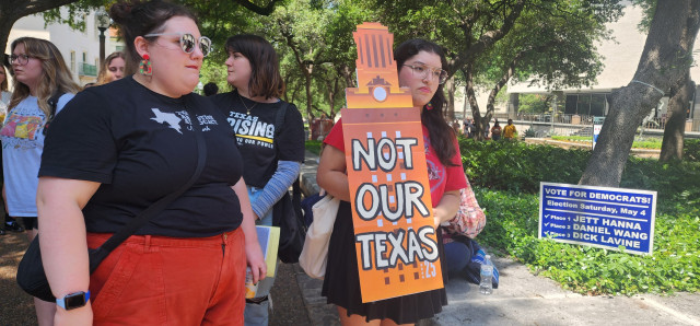 Students hold a sign of the clock tower in UT orange, labeled "Not Our Texas."