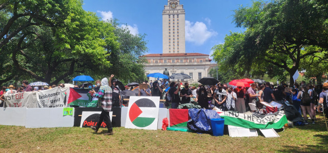 Activists protect tents with signs and linked arms under the shadow of the UT clock tower. 
