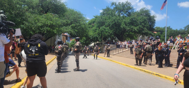 Rows of state troopers in riot helmets are on the UT campus by the clock tower. 